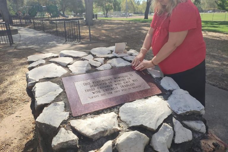 Tracy Ferris adheres a QR code to a Children's Memorial containing archived articles from 1964.