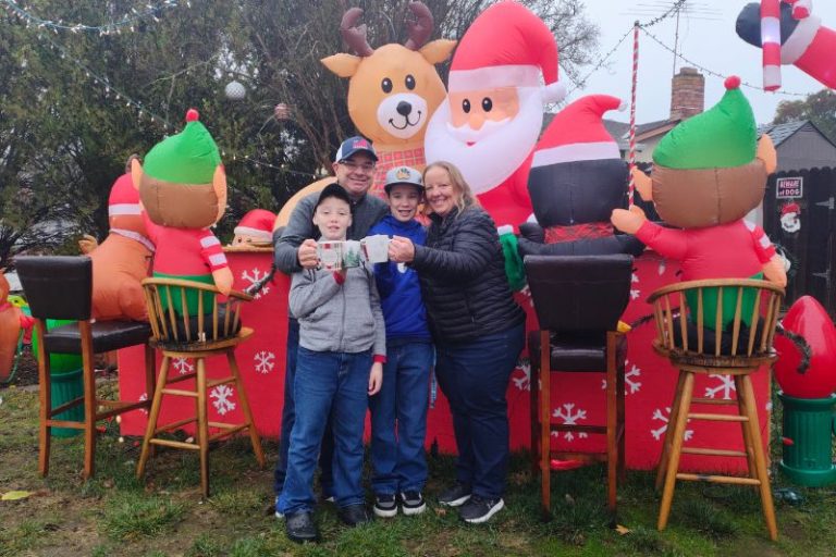 The Simpson family stands in front of a custom built hot cocoa bar featuring Santa and several other winter and Christmas inflatable characters. // SB Williams